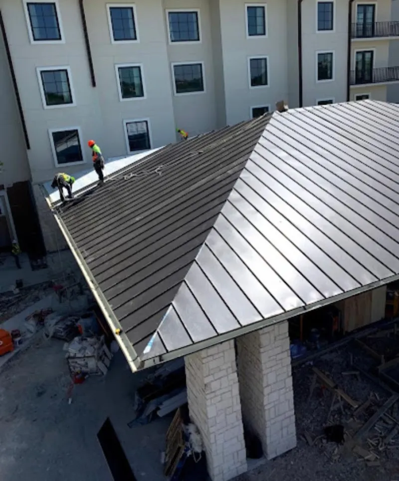 Crew installing standing seam metal roof panels on a commercial project in New Milford